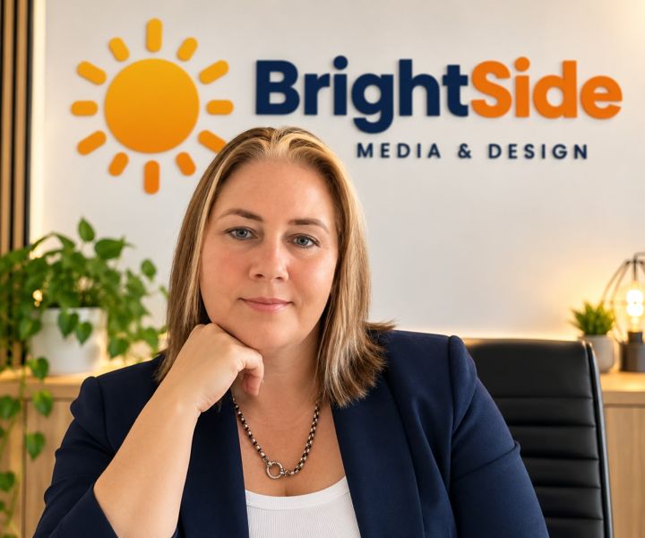 Charne Smit of BrightSide Media & Design, smiling at her desk in front of the BrightSide logo